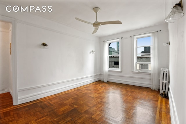 empty room with radiator, ceiling fan, and baseboards