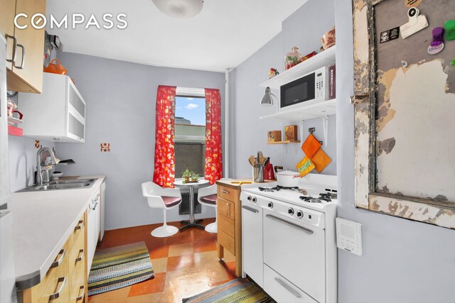 720 W 173rd St Unit 59, New York City, NY 10032 - kitchen with white appliances, a sink, open shelves, tile patterned floors, and light countertops
