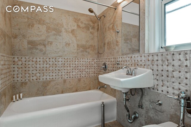 full bath featuring  shower combination, a sink, and tile walls