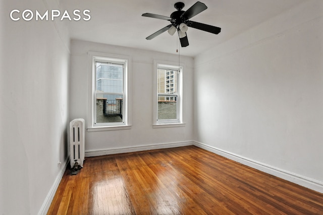 empty room with radiator, ceiling fan, wood-type flooring, and baseboards