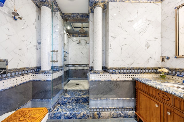 full bath with vanity, a marble finish shower, and tile walls