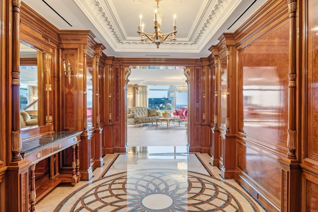 hallway featuring ornamental molding, a tray ceiling, a notable chandelier, and wood walls