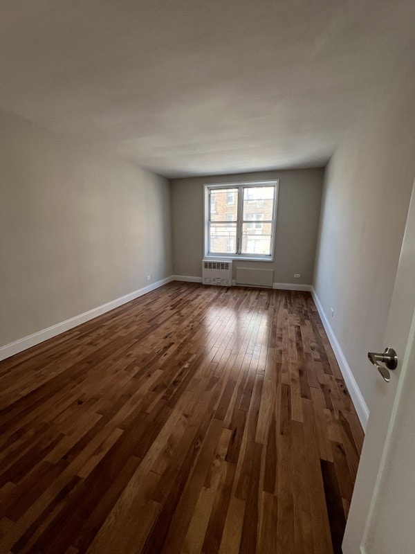 unfurnished room featuring baseboards and dark wood-style flooring