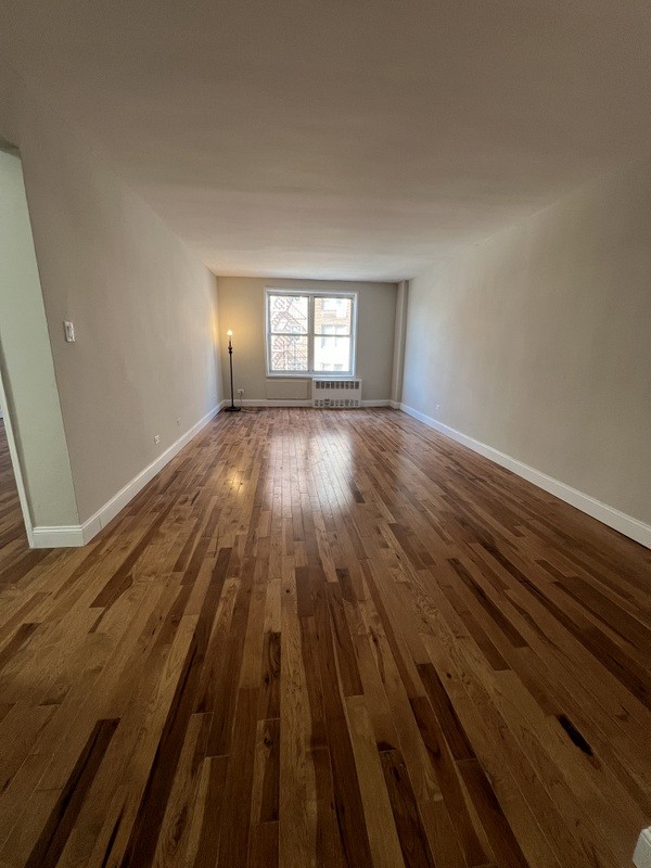 interior space featuring dark wood-type flooring, a wall unit AC, and baseboards