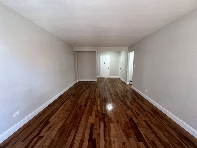 unfurnished living room with baseboards and dark wood-style flooring