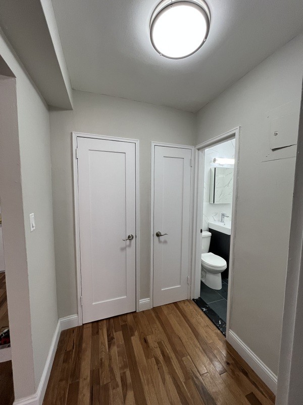 interior space featuring vanity, toilet, wood finished floors, and baseboards