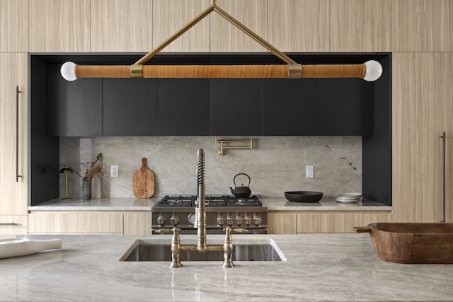 kitchen featuring a sink, modern cabinets, tasteful backsplash, and high end stove