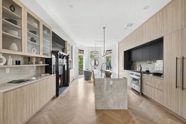 kitchen with light brown cabinets, modern cabinets, high end stainless steel range, and a kitchen island with sink