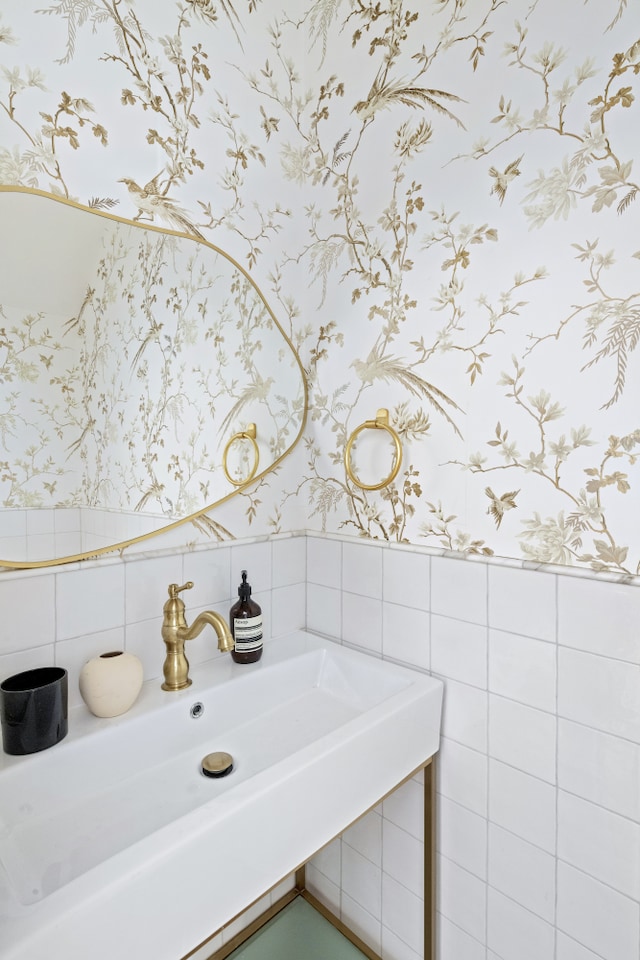 bathroom featuring a sink, wainscoting, and wallpapered walls