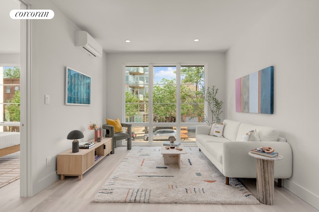 living room with baseboards, plenty of natural light, an AC wall unit, and light wood-style floors