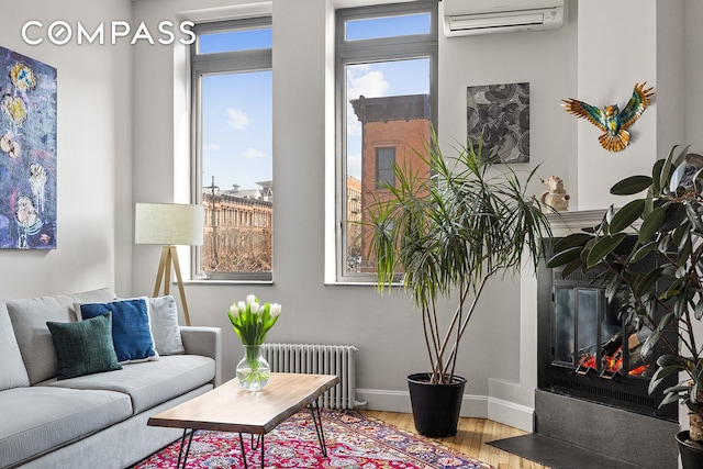 living area featuring a healthy amount of sunlight, radiator, a wall unit AC, and wood finished floors