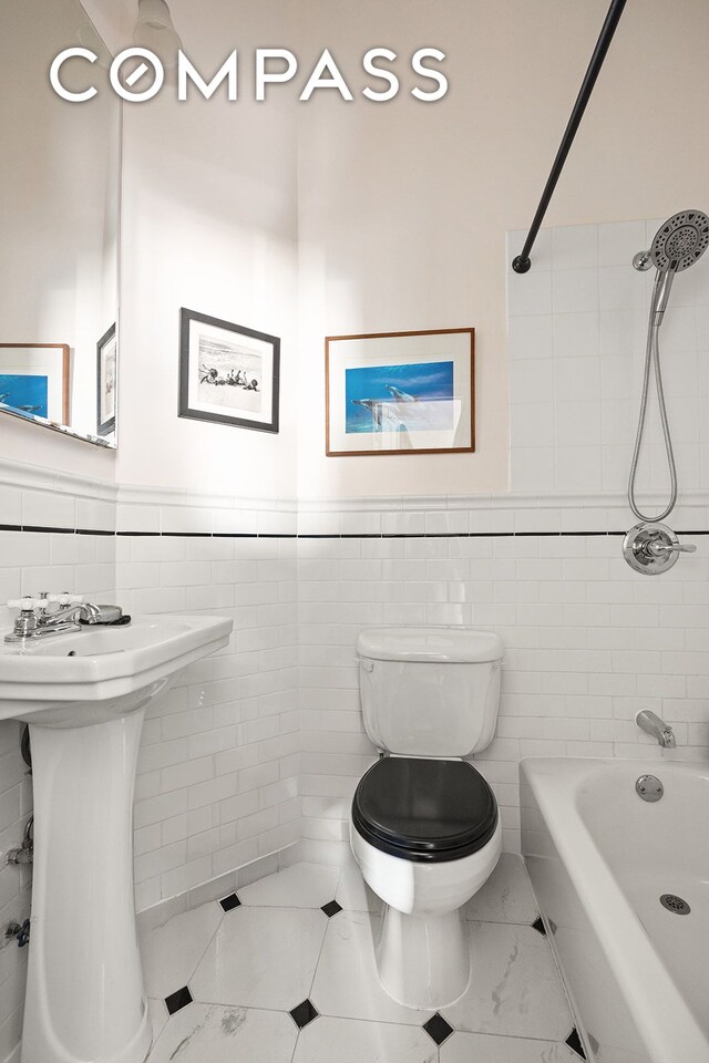 full bathroom featuring wainscoting, toilet, tile walls, and bathing tub / shower combination