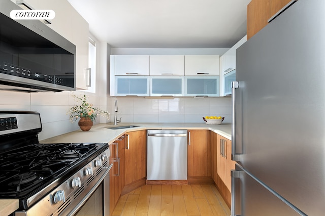 kitchen with stainless steel appliances, modern cabinets, a sink, and light countertops