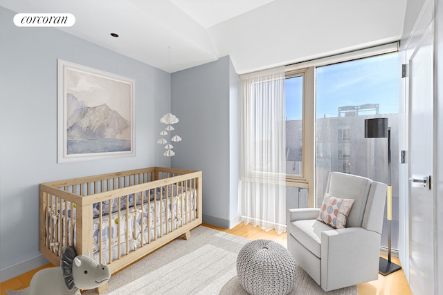 bedroom featuring baseboards, a nursery area, and wood finished floors