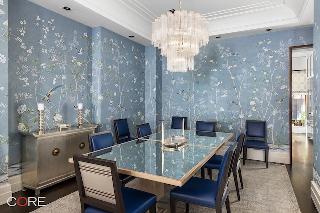 dining area with wallpapered walls, ornamental molding, wood finished floors, a tray ceiling, and a chandelier