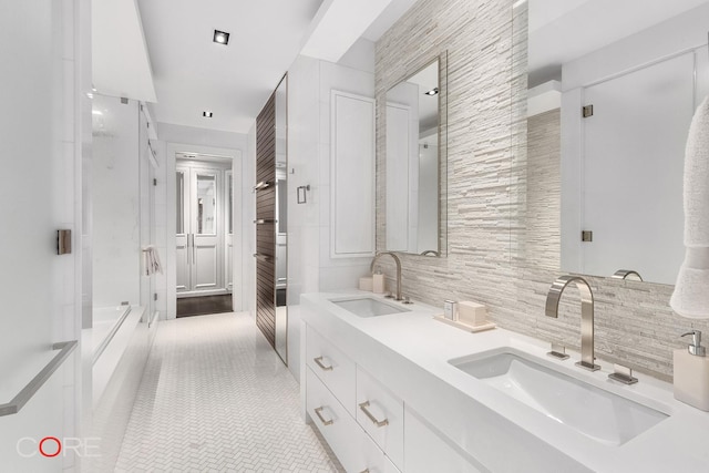 bathroom featuring tasteful backsplash, tile patterned flooring, a sink, and double vanity