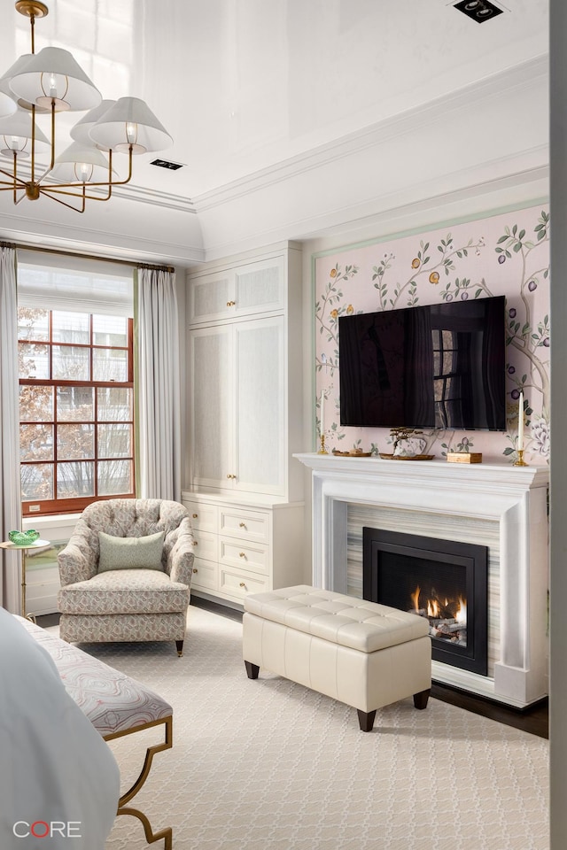 sitting room featuring a warm lit fireplace, visible vents, crown molding, carpet floors, and a chandelier