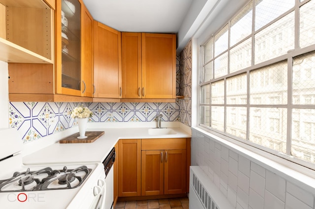 kitchen with brown cabinets, light countertops, radiator heating unit, a sink, and white appliances