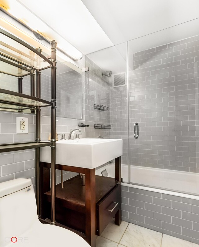 full bath featuring tile walls, visible vents, toilet, a tile shower, and vanity