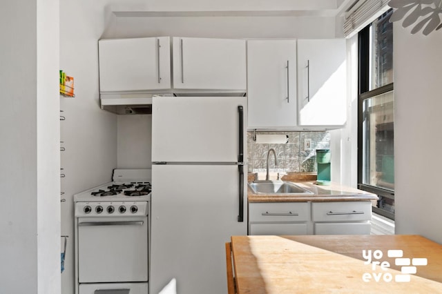 kitchen with white appliances, plenty of natural light, a sink, and white cabinets