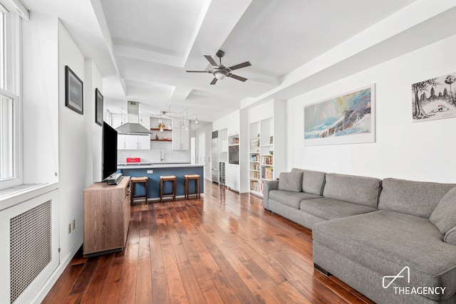 living area with beam ceiling, dark wood finished floors, visible vents, a healthy amount of sunlight, and ceiling fan