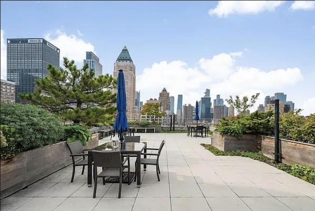 view of patio / terrace featuring a city view, outdoor dining area, and fence