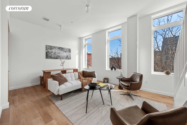 living room featuring plenty of natural light, light wood-type flooring, and visible vents