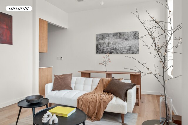 living area with light wood-style flooring, visible vents, and baseboards