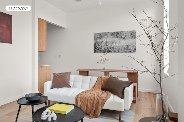 living area with visible vents, light wood-style flooring, and baseboards