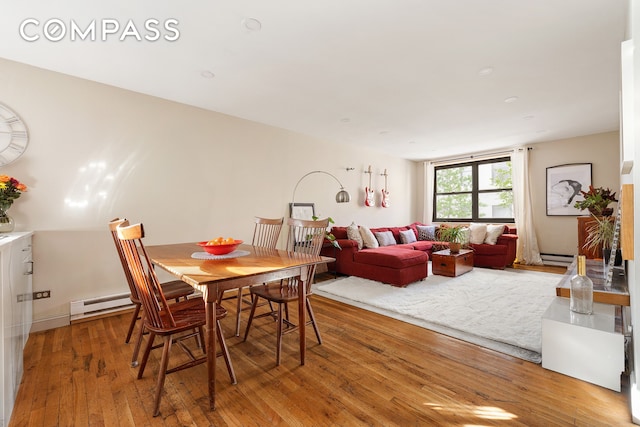 dining area featuring a baseboard radiator and hardwood / wood-style flooring