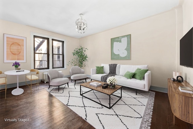 living area featuring baseboards, an inviting chandelier, and hardwood / wood-style flooring