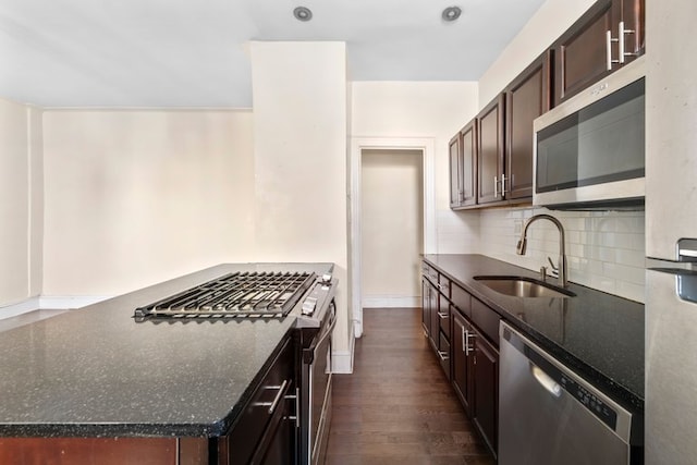 kitchen featuring a sink, dark stone countertops, tasteful backsplash, stainless steel appliances, and dark brown cabinetry