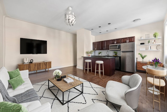 living room featuring an inviting chandelier, dark wood-style floors, and baseboards