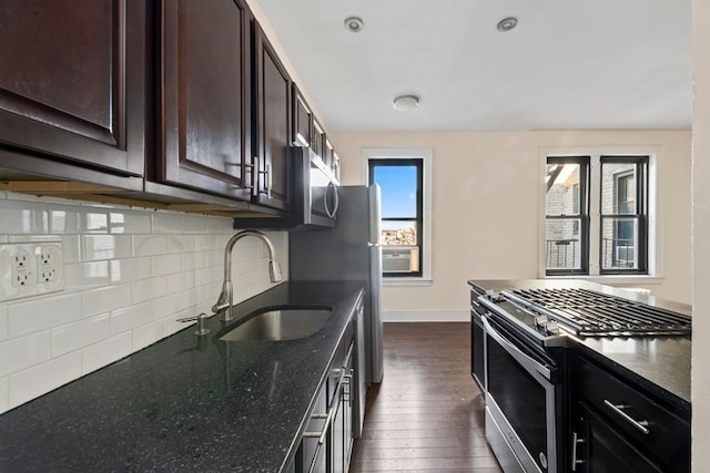 kitchen featuring dark wood-style floors, a sink, dark brown cabinets, appliances with stainless steel finishes, and tasteful backsplash