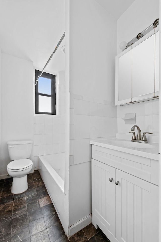 bathroom with stone finish flooring, toilet, vanity, tile walls, and  shower combination