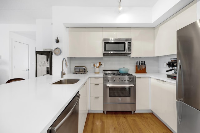 kitchen with stainless steel appliances, light wood-style flooring, a sink, and light countertops