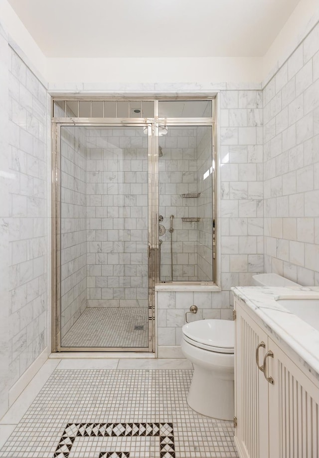 full bathroom with tile patterned flooring, toilet, vanity, tile walls, and a stall shower