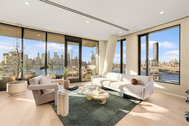 living room with a city view, a wall of windows, recessed lighting, and wood finished floors