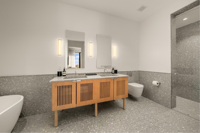 bathroom featuring double vanity, a freestanding tub, wainscoting, and a sink