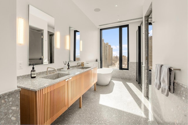 full bath featuring double vanity, a freestanding bath, and a sink