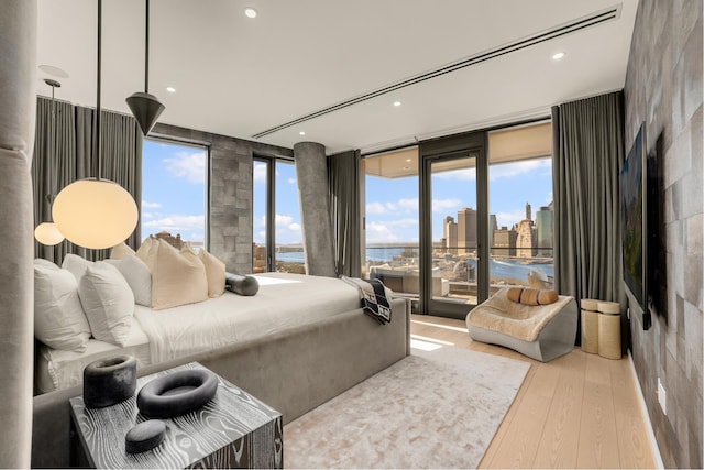 bedroom featuring wood finished floors, access to outside, expansive windows, a city view, and recessed lighting