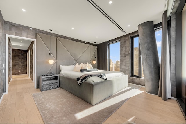 bedroom with light wood finished floors, recessed lighting, and a city view