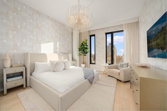 bedroom with wallpapered walls, light wood-style flooring, and an inviting chandelier