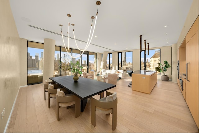 dining area with light wood finished floors, a wall of windows, a city view, and recessed lighting