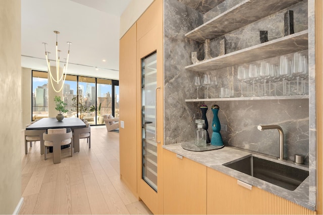 bar with a view of city, floor to ceiling windows, light wood finished floors, backsplash, and a sink