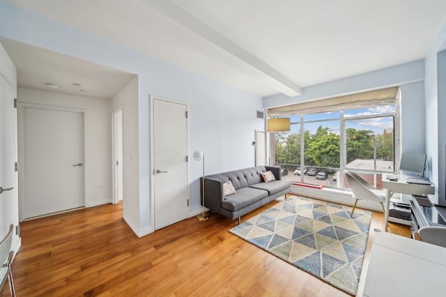 living room with baseboards, beamed ceiling, and light wood-style floors