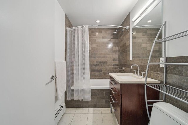 bathroom featuring tile walls, a baseboard radiator, toilet, tiled shower / bath combo, and vanity