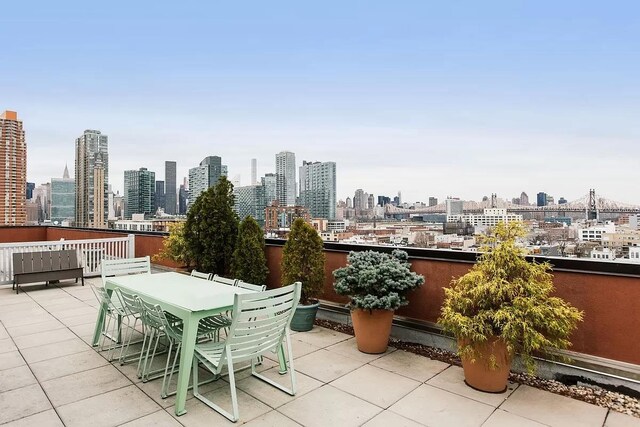 view of patio / terrace featuring a view of city, outdoor dining area, and a balcony