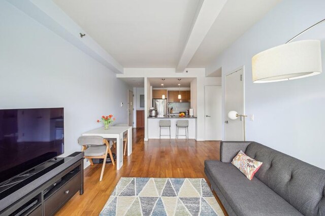 living room featuring beamed ceiling and light wood-style flooring