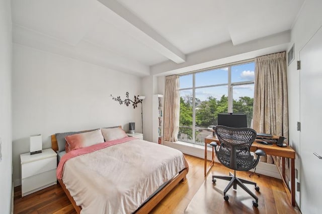 bedroom featuring visible vents, beamed ceiling, and wood finished floors